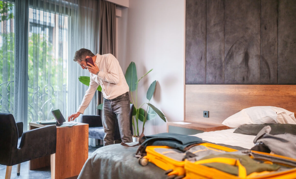 Businessman talking on mobile phone in hotel room.