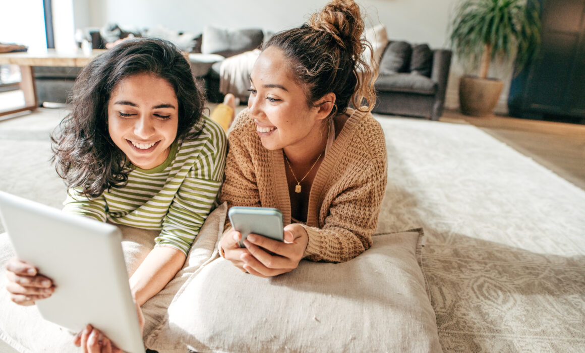 Two female students with digital tablet and cellphone at home