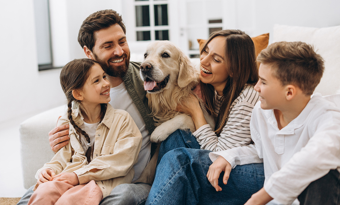 A happy and smiling family of four hugging their Golden Retriever dog in Corporate Housing.