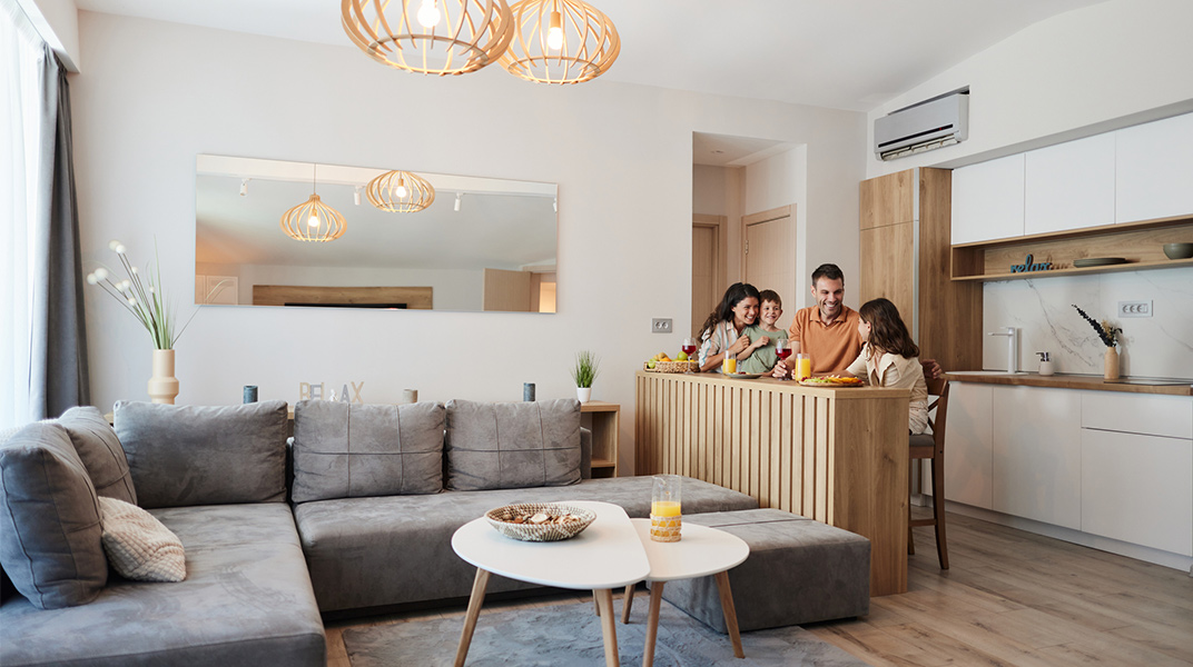 Family talking and eating breakfast at the bar counter in the kitchen of a furnished corporate housing apartment during relocation