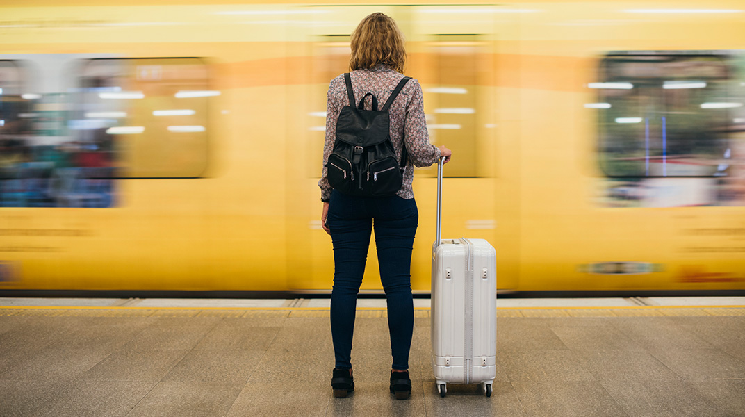 Business traveler with suitcase waiting for train during extended assignment travel