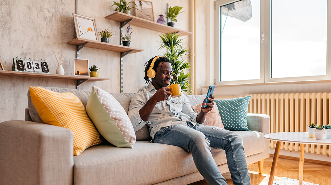 Employee working remotely from a fully furnished corporate housing apartment with comfortable living space, kitchen amenities, and natural light.