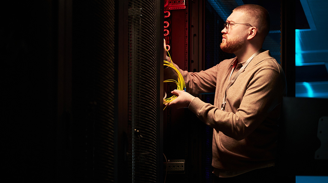Technician working on network cabling inside a modern data center supporting AI infrastructure projects