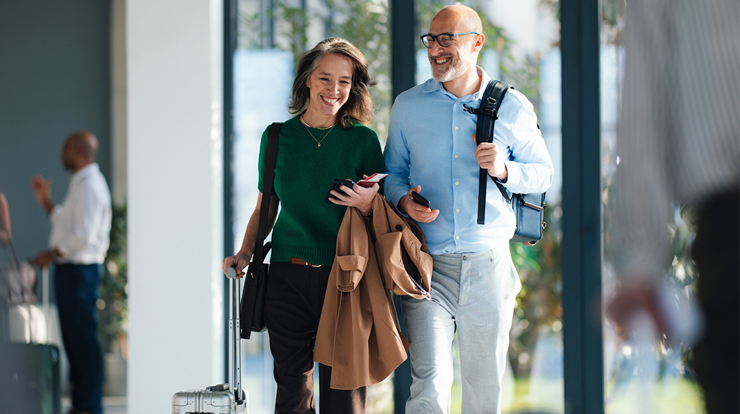 Business travelers with luggage walking through a modern building, representing workforce mobility and corporate housing support.